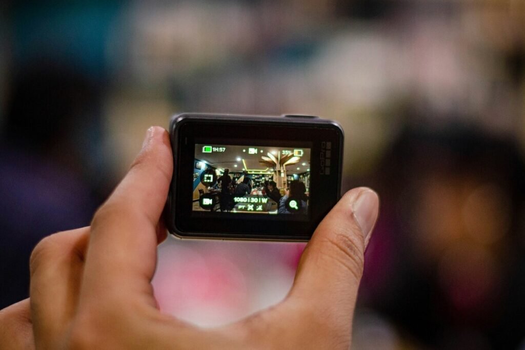 The picture shows a hand holding a GoPro action camera filming a scene in a shopping mall on the website of 'The House Technology', specialists in action cameras and accessories for GoPro and Insta360.