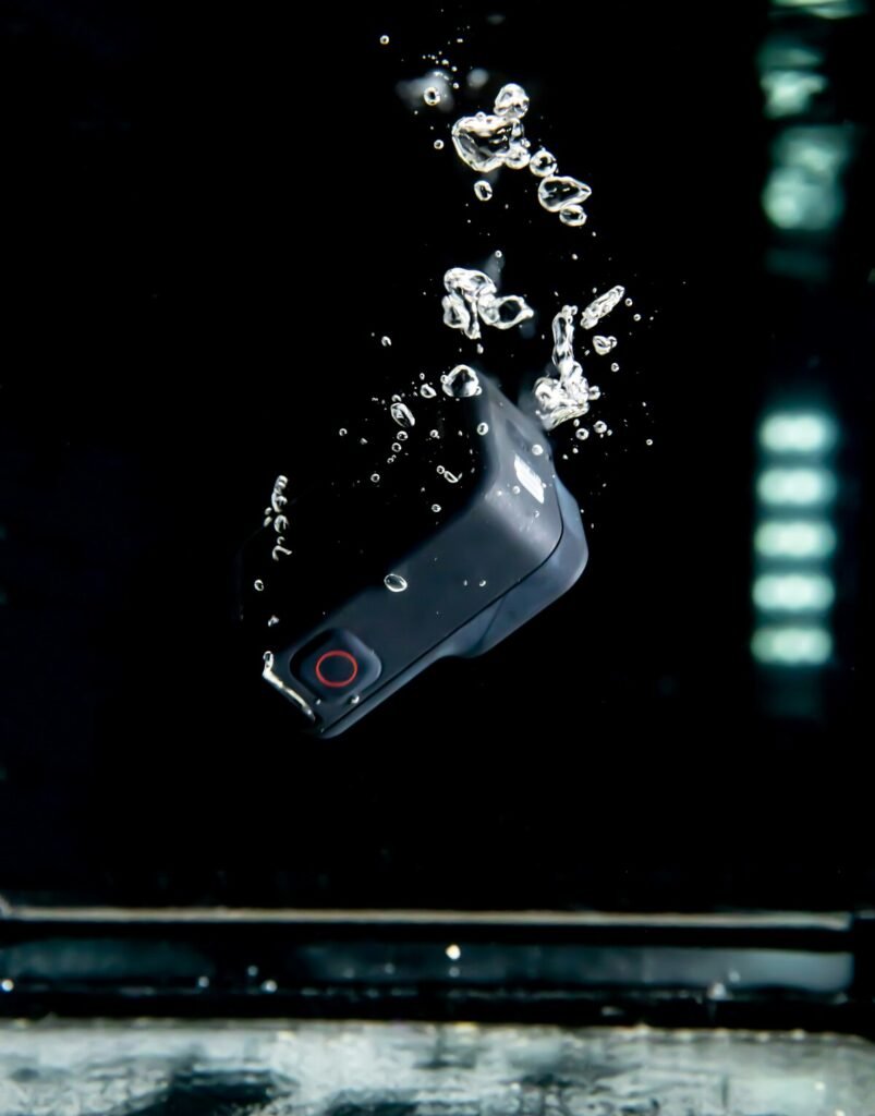 The picture shows an action camera sinking to the ground of a vessel filled with water. There are bubbles raising above the falling camera. The camera is a GoPro action camera. The picture is a decorative element of the business website of 'The House Technology', which specialises in action cameras and accessories. They offer a technical service to repair broken action cameras as well, therefore the image of a drowning camera was used.